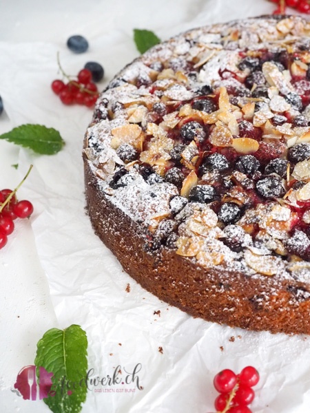 Beerenkuchen mit Blaubeeren, Himbeeren und Johannisbeeren mit Puderzucker bestäubt.