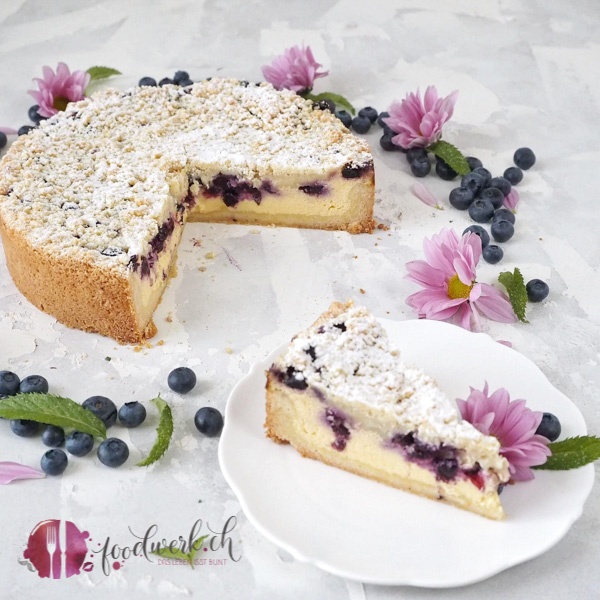 Quarktorte mit Blaubeeren und Streuseln angeschnitten.