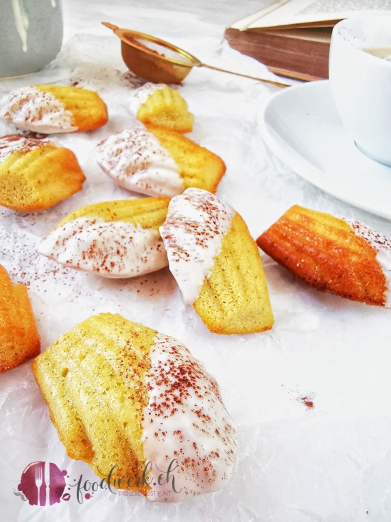 Cappuccino Madeleines auf Backpapier mit Kakaopulver und Kaffee