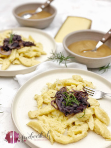 Quarkpizokel auf hellem Teller mit Zwiebelschweize und Apfelmus
