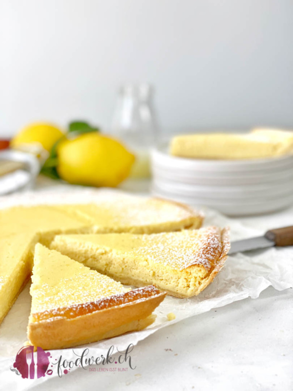 Ricotta Tarte angschnitten mit den Zutaten im Hintergrund