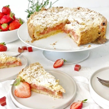 streuselkuchen mit erdbeeren und rhabarber auf weiser kuchenplatte serviert