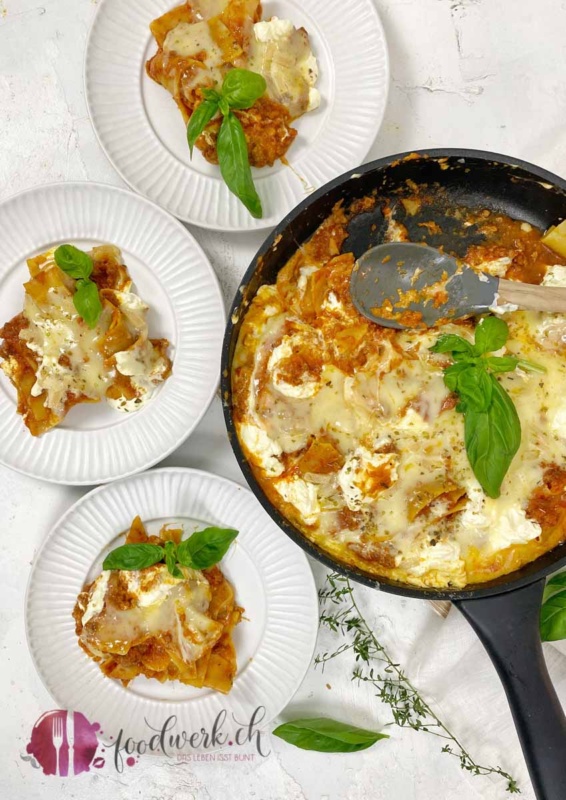 Drei Teller mit Pfannen Lasagne und Raclette Suisse Käse