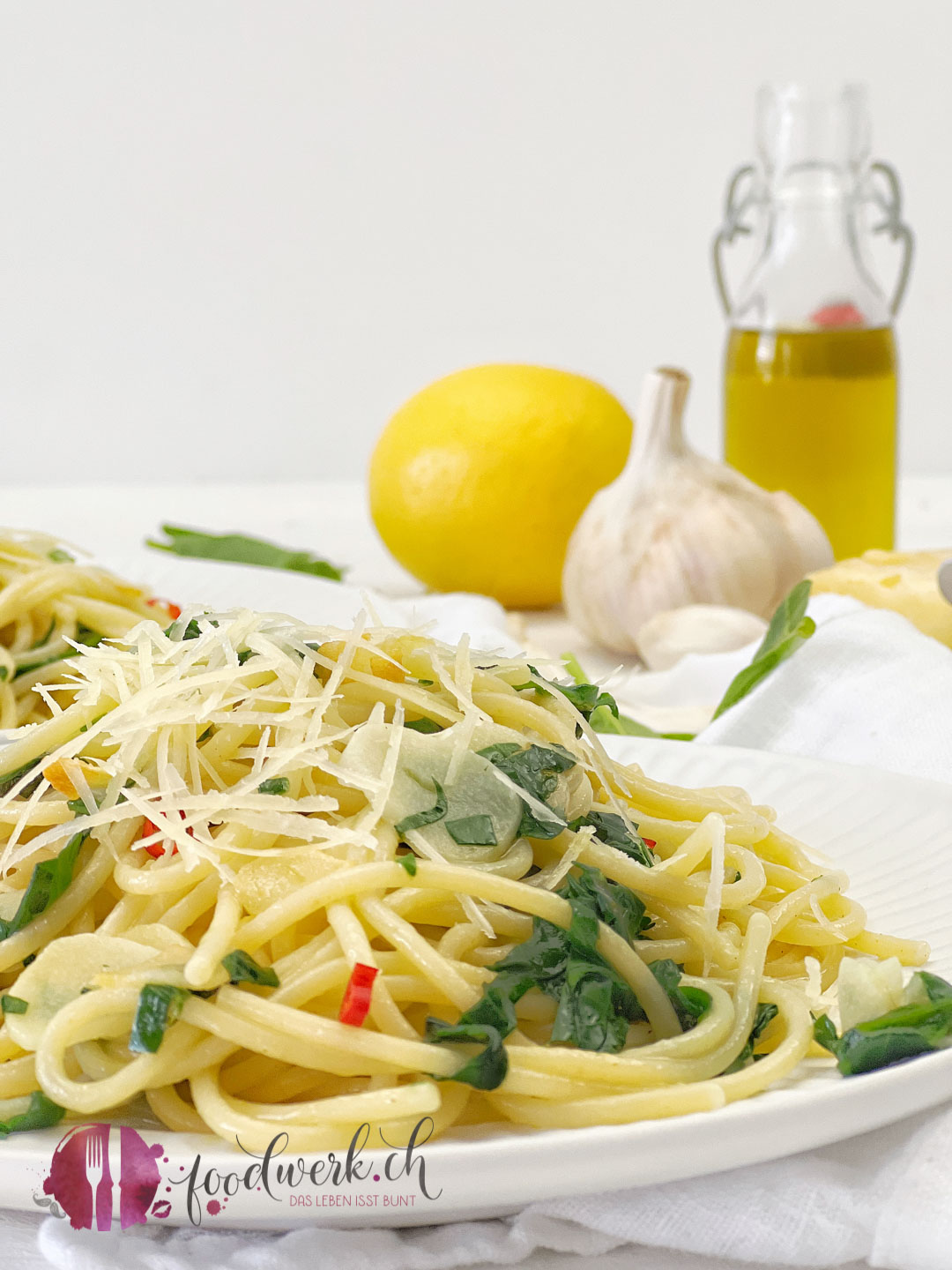 SPaghetti aglio e olio nah mit Olivenöl und Knoblauch im Hintergrund