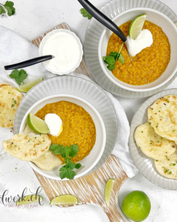 Linsen Dal angerichtet in weissen Schalen mit Naan Brot