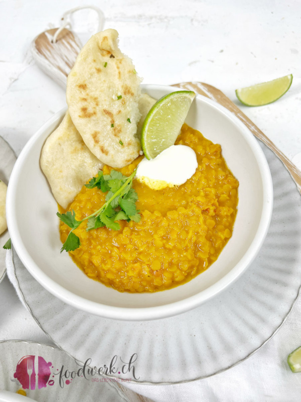 Eine Portion Linsen Dal aus roten Linsen mit Limette und Naan Brot