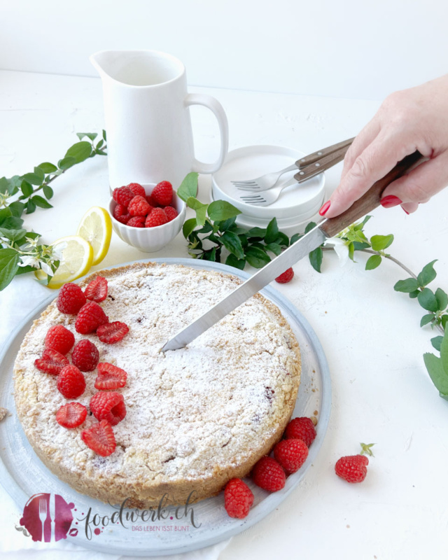 Saftiger Himbeeren Kuchen mit Streusel und Quark anschneiden