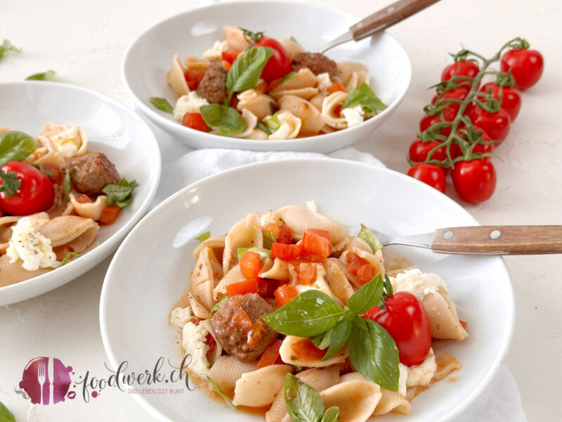 Pasta Caprese Art im Teller mit Zweigtomaten